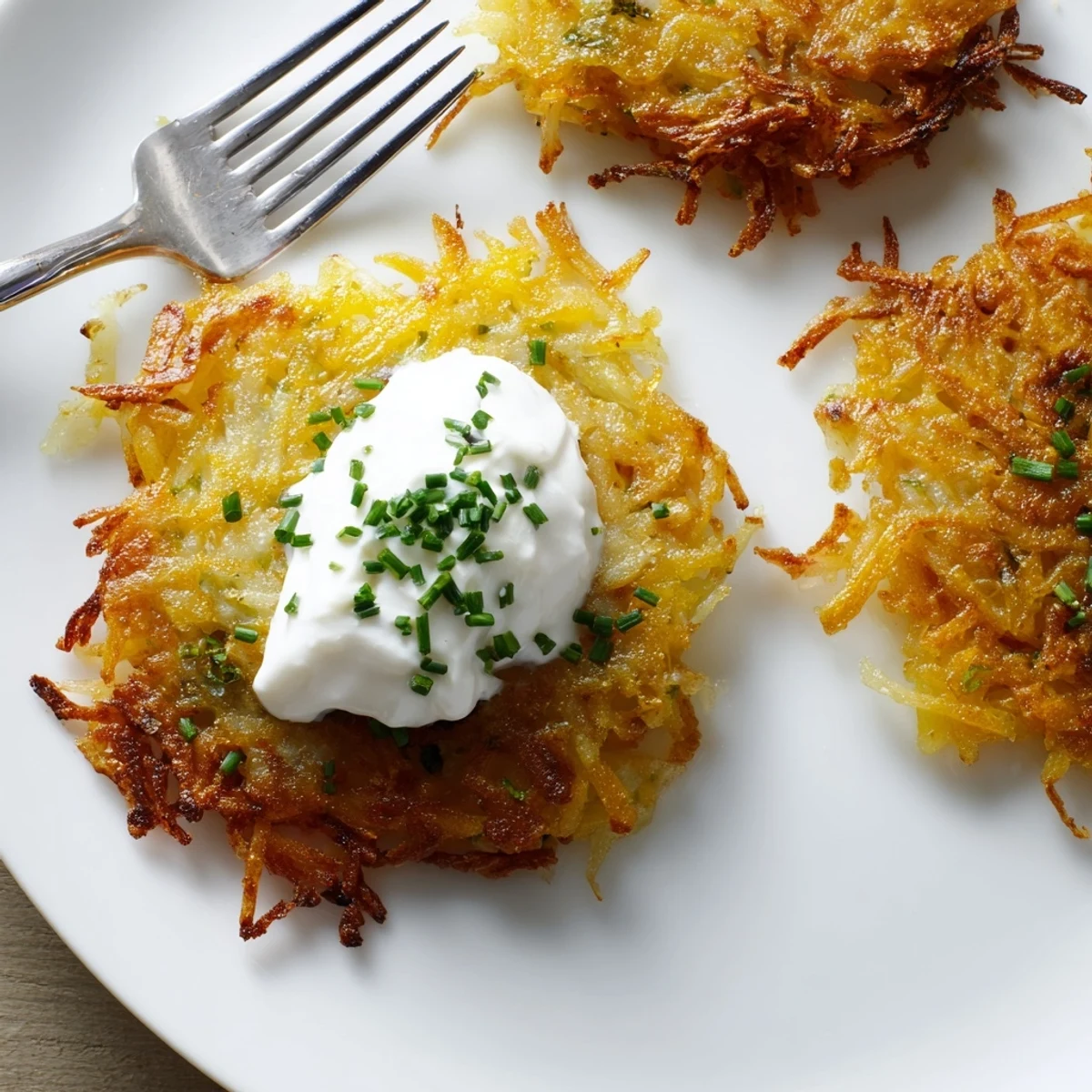 Goldene, knusprige Kartoffelpuffer mit Sauerrahm und frischen Kräutern serviert.  
